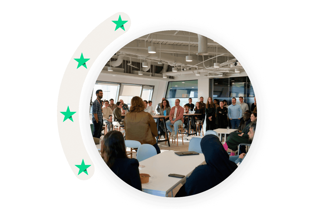 A photo in a circle shape showing Trustpilot employees participating in a meeting.
